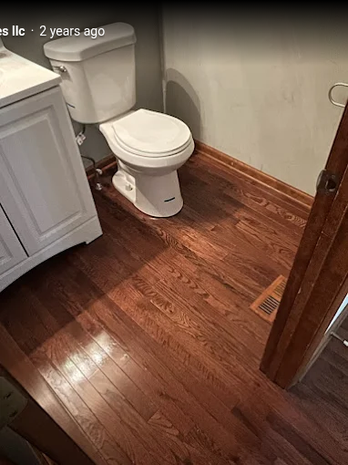 Installed white toilet beside bathroom vanity on hardwood floor