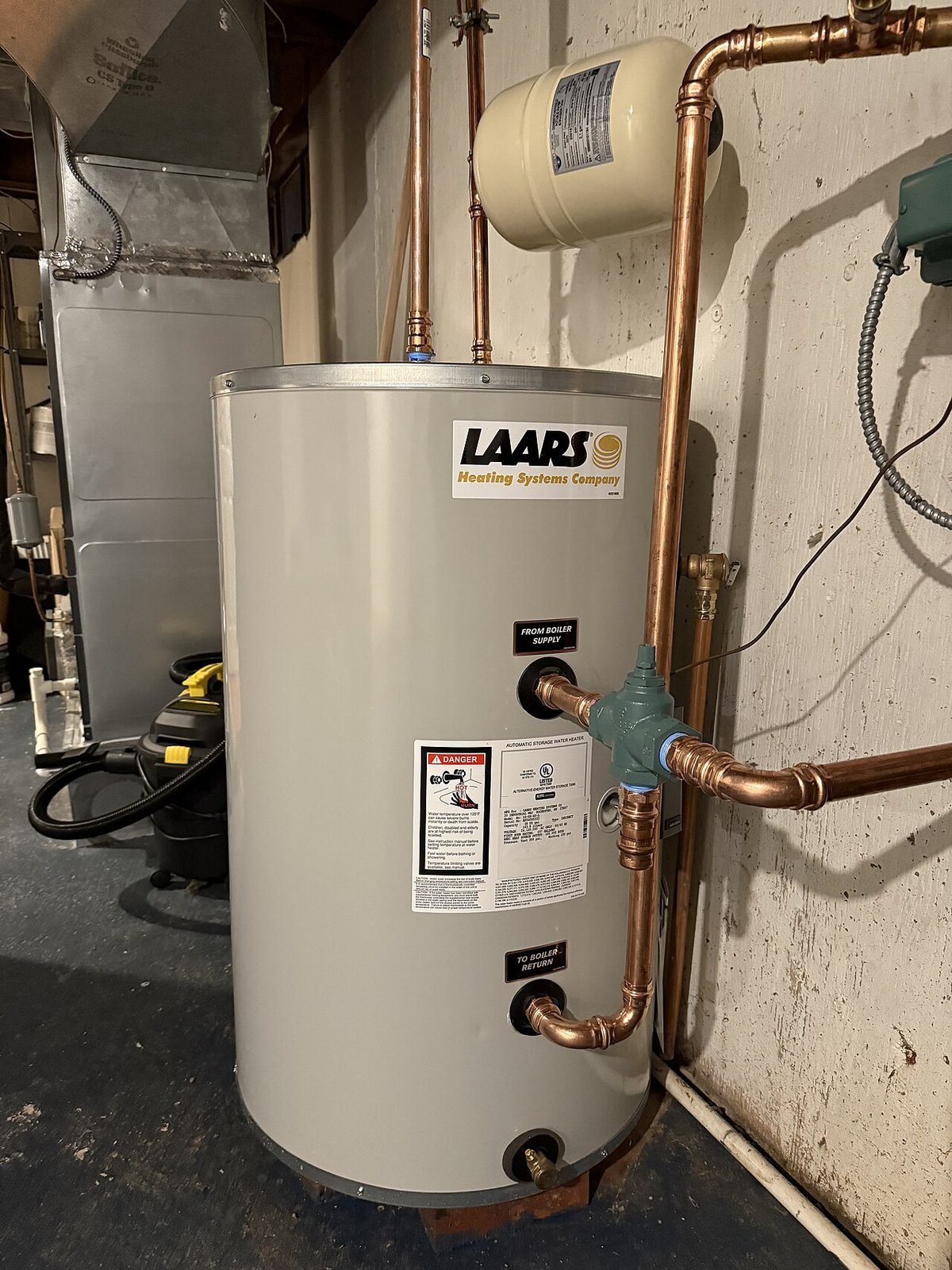 Newly installed storage water heater with copper piping in a basement utility room