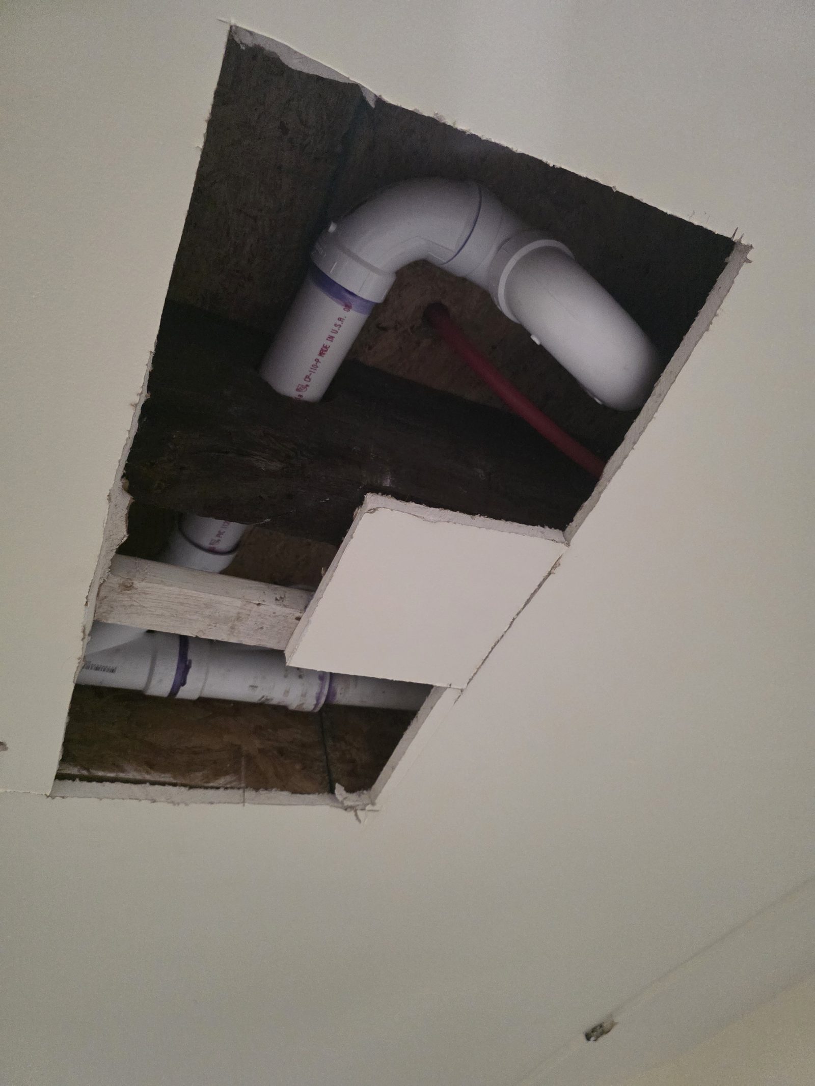 Ceiling access opening showing in-wall PVC plumbing